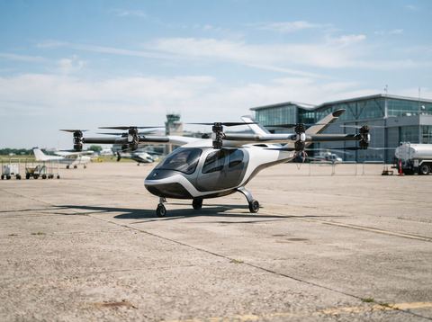 An electric vertical takeoff and landing aircraft prototype parked on a sunny airfield tarmac.
