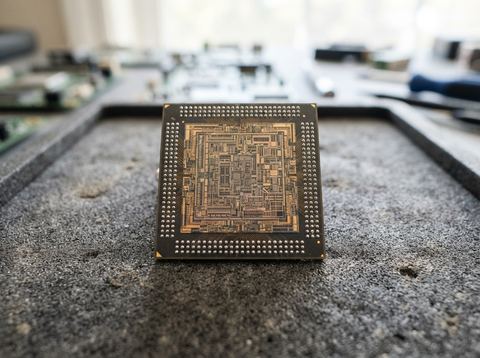 Close-up of a silicon microchip with visible circuitry on an anti-static tray under bright light.