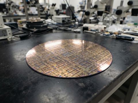 A large specialized silicon chip resting on a workbench in a bright semiconductor lab.