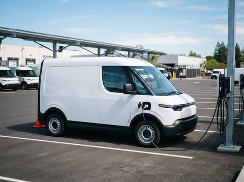 A zero-emission electric delivery van parked in a sunlit commercial fleet yard.