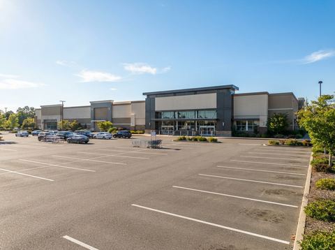 Wide view of a large retail store exterior with a spacious parking lot under a clear sky.