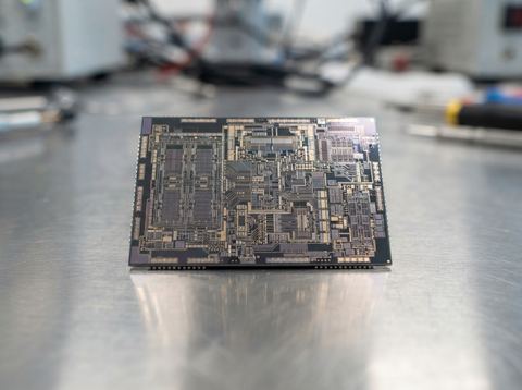Close-up of a semiconductor chip with visible circuit patterns under bright studio light.