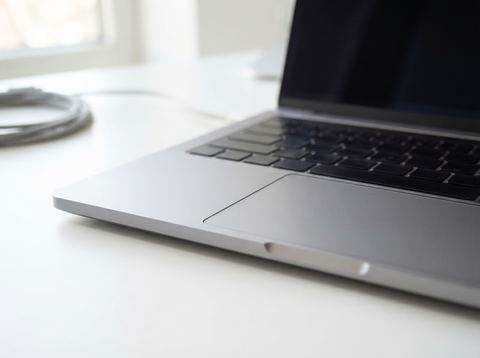 Close-up of a brushed aluminum laptop chassis on a bright workbench, representing American computer hardware manufacturing.